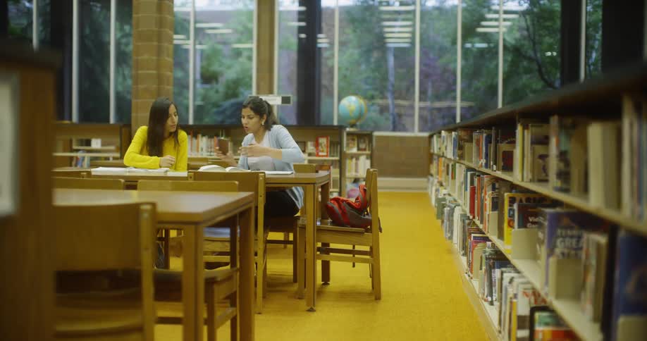 People are in a library looking at a phone
