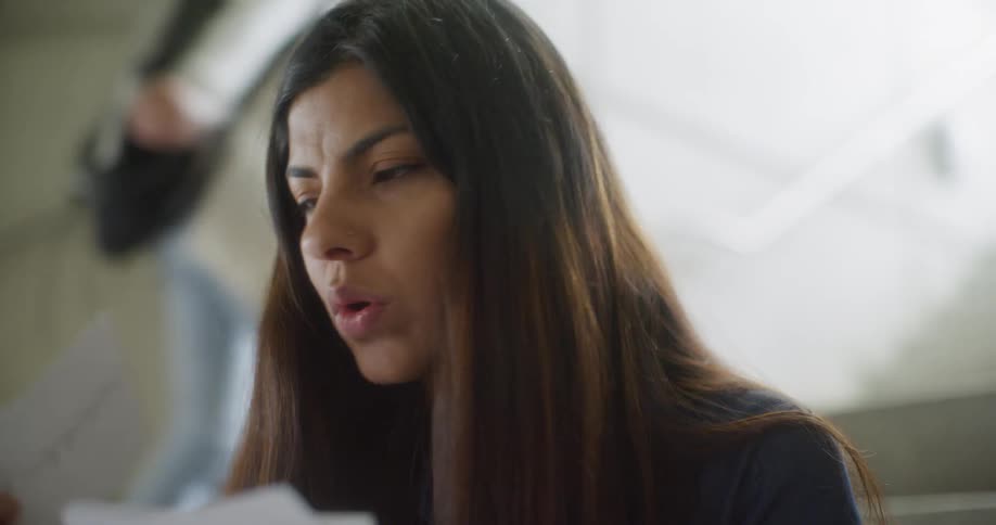 A woman is reacting to some papers she is reading