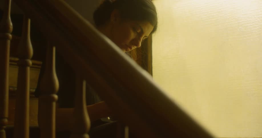 A female sits on the stairs and uses her phone