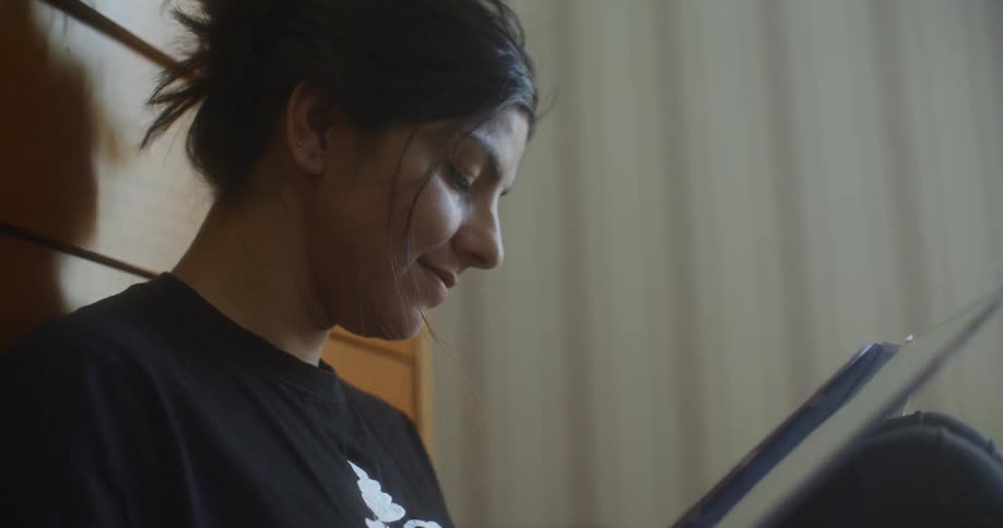 Woman leaning on drawer looks at photo album