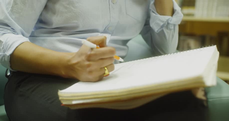 Woman on phone writes in notebook