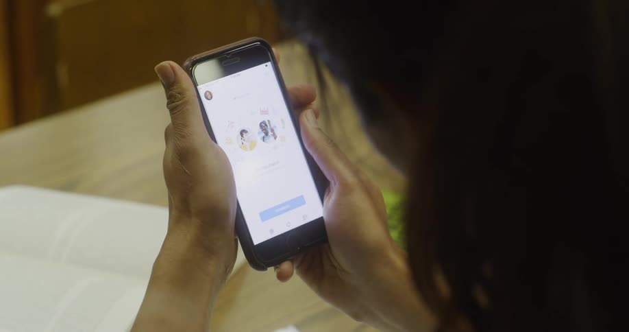 A woman takes a break from a book to look at her phone