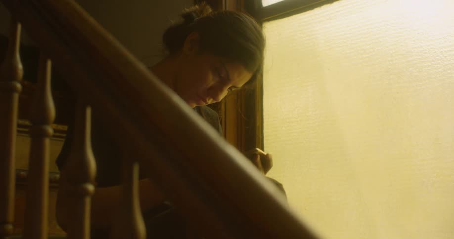 A woman uses a phone while sitting on stairs