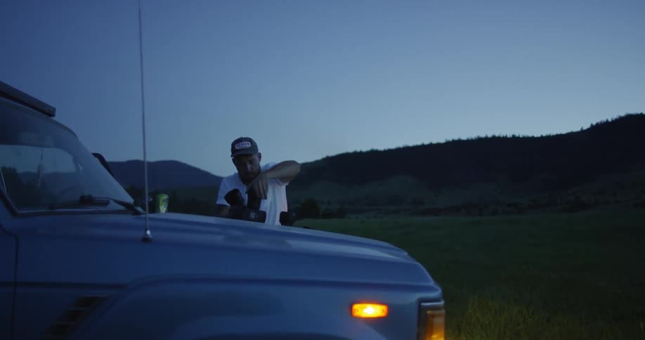 Photographer putting lenses on his camera while outside his vehicle