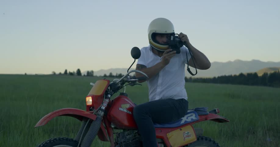 A man on a honda dirt bike takes photos