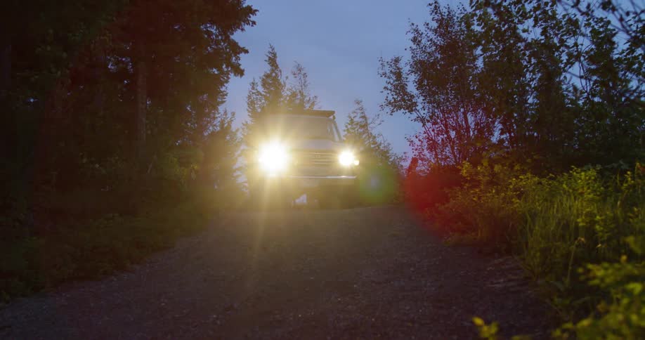 A vehicle turns its lights on and starts to drive