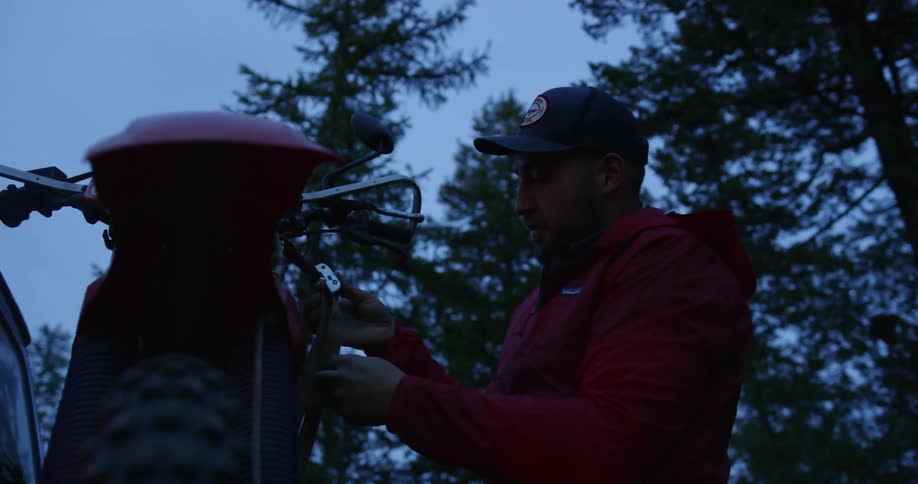A man is securing his motorcycle in to the back of his truck