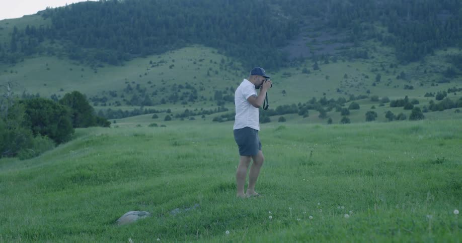 A man takes photos with a camera in a large hilly field