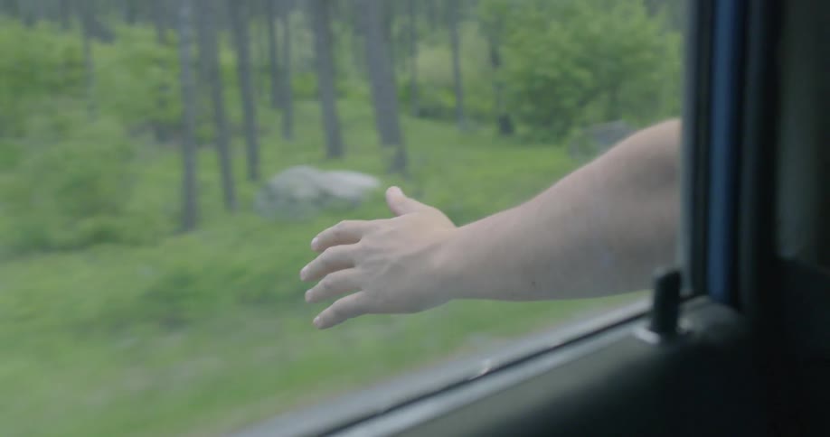 A man holds his arm outside of a moving car
