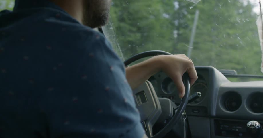 A man driving a vehicle on a road surrounded by trees