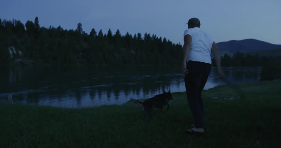 A man plays fetch with his dog at the river