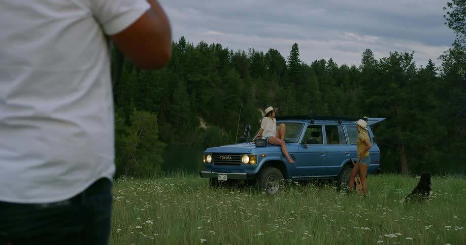 Two woman are by a car outdoors