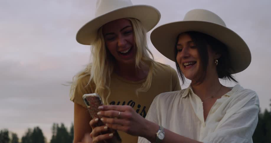 Two woman are looking at a phone outdoors