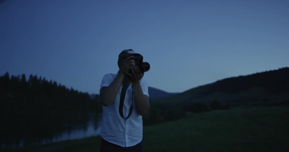 A man stands taking photos at nighttime