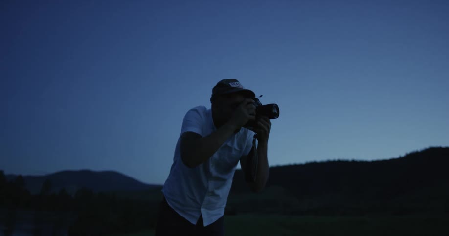 A man takes photos using an slr camera at twilight