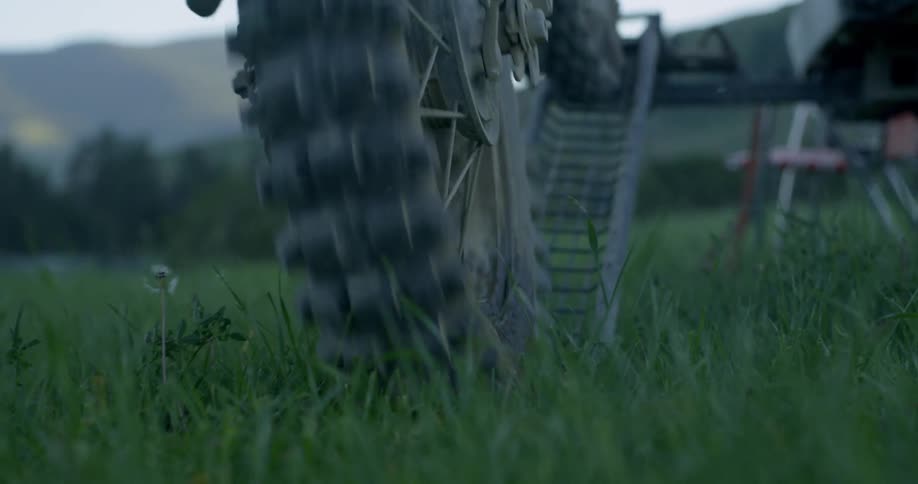 A man rolls a dirt bike down a ramp in a rural field