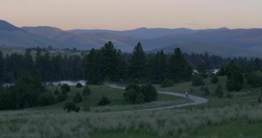 Man rides motorcycle on forest road at dusk