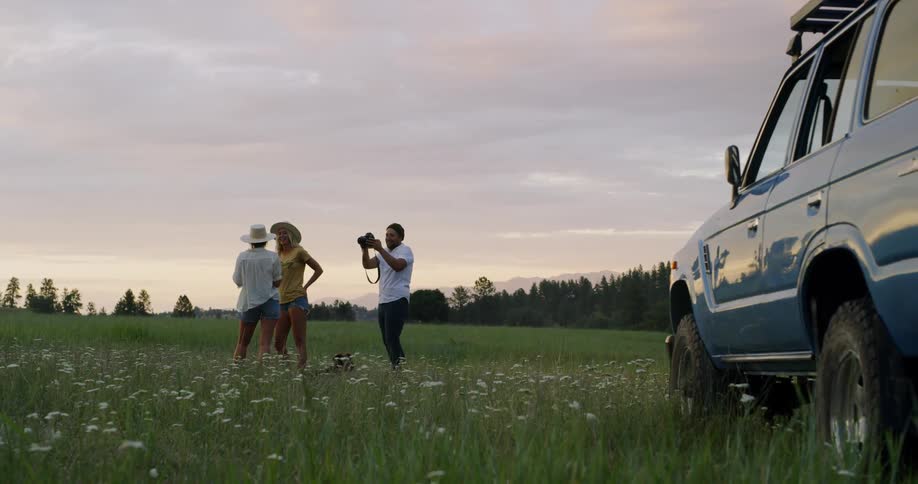 Man photographs two women in field
