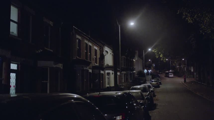 View of cars parked up and down a street at night
