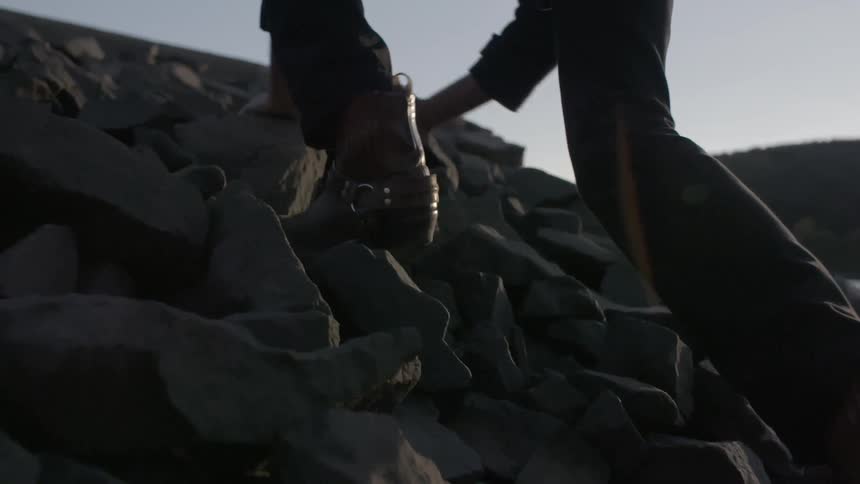 A person wearing boots climbing up rocks