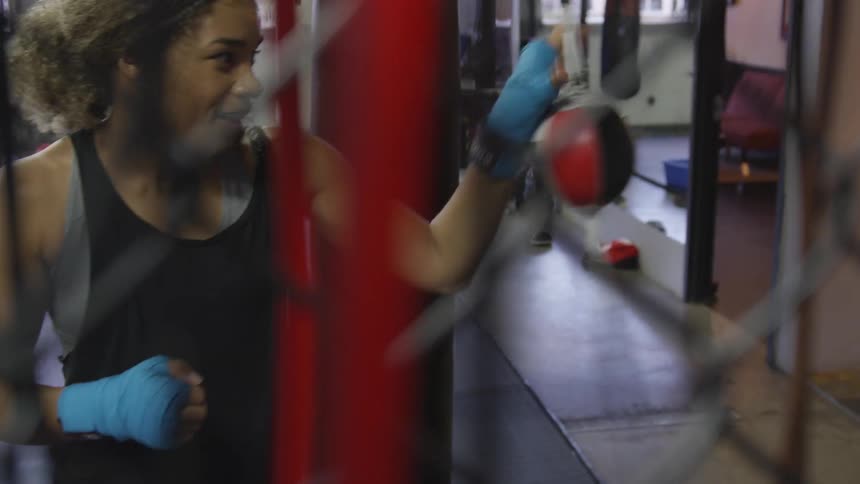 A woman trains by punching a speed bag