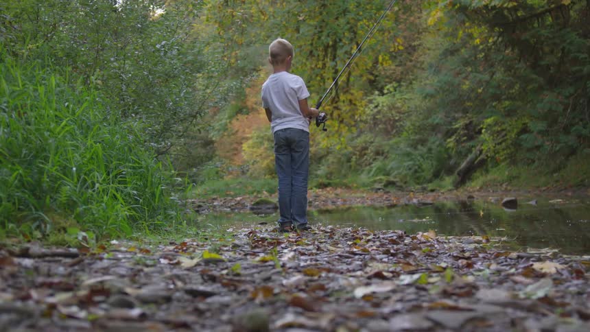 A boy is holding a fishing pole outdoors