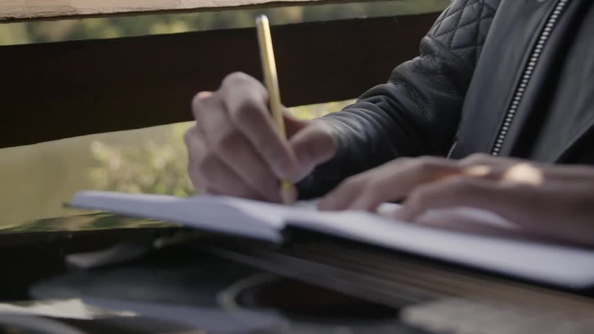 A person using a pencil to write in a book
