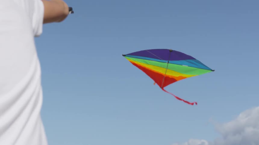 A child is flying a rainbow colored kite