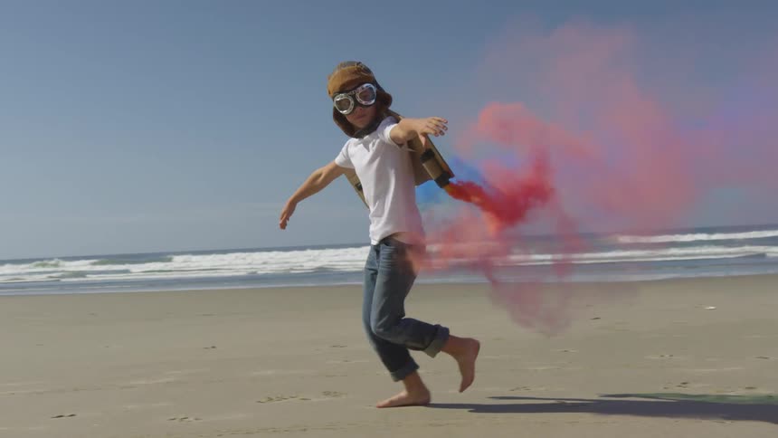Boy runs on beach with artificial wings on his back