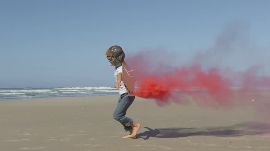 A person running around a beach with red smoke coming out of their back
