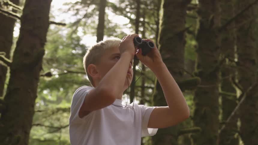 A young blond haired boy looks through a pair of binoculars