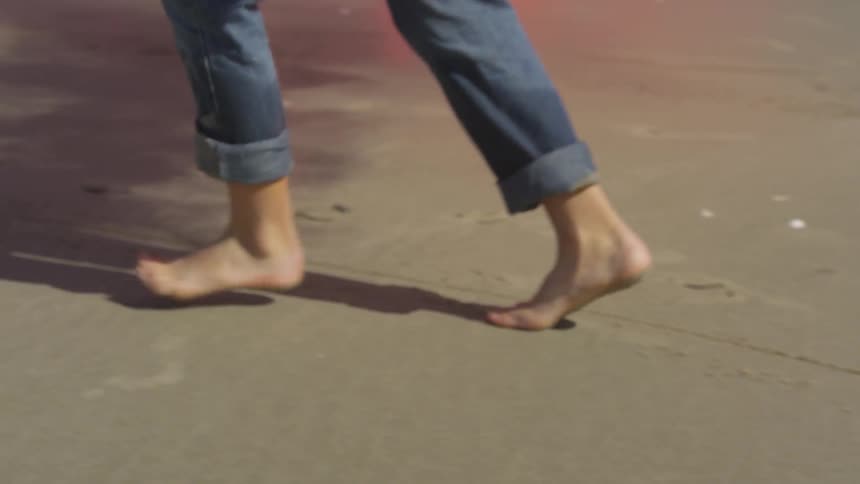 A person is running in the sand with a smoke can
