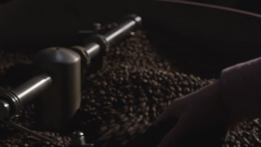 A person is holding beans that are being spun in a machine