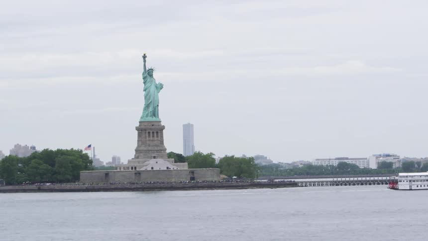 A boat floats by the statue of liberty