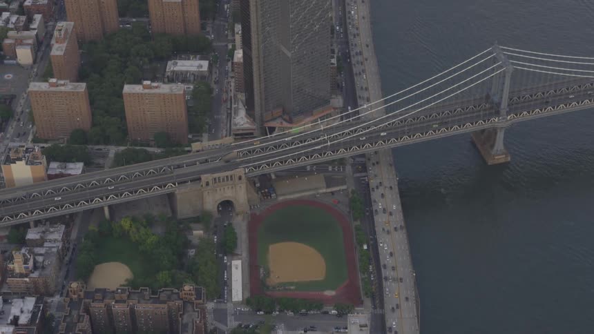 A bridge leading past apartments and ball fields surrounded by city life