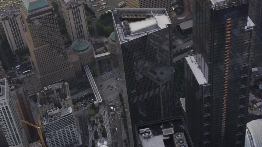 The vehicles drive on the street past the tall buildings