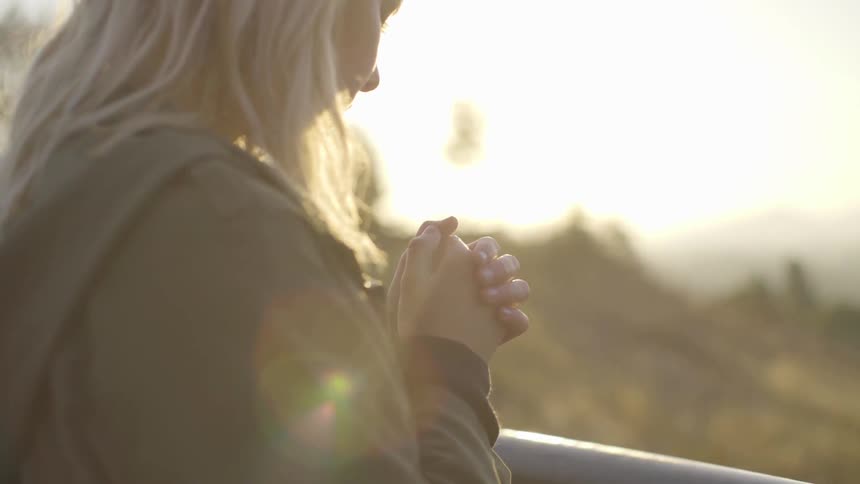 A woman with her hands cupped together standing in the sun