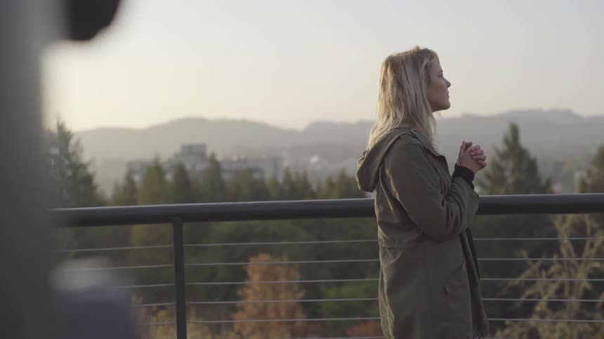 Woman clasps hands in prayer while outside