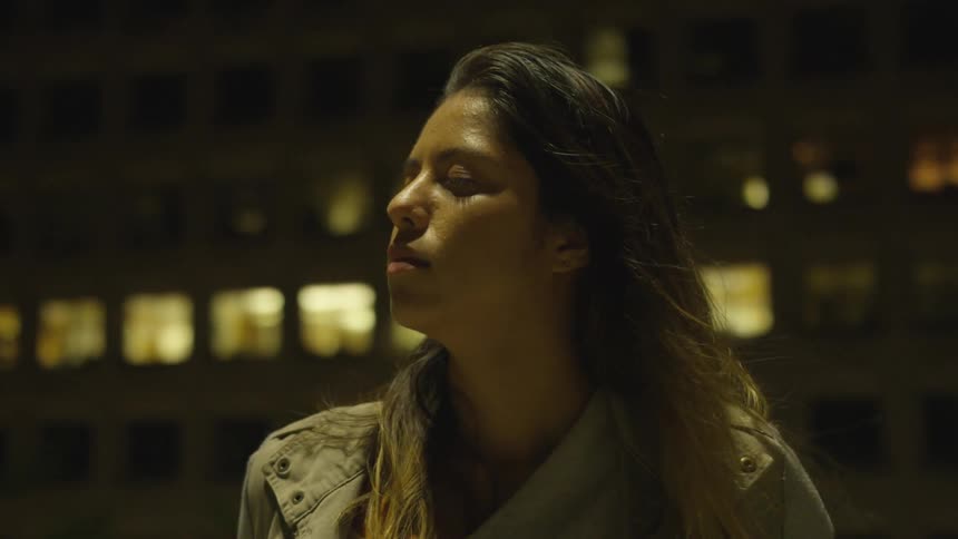 A woman enjoys a breeze blowing her hair at night