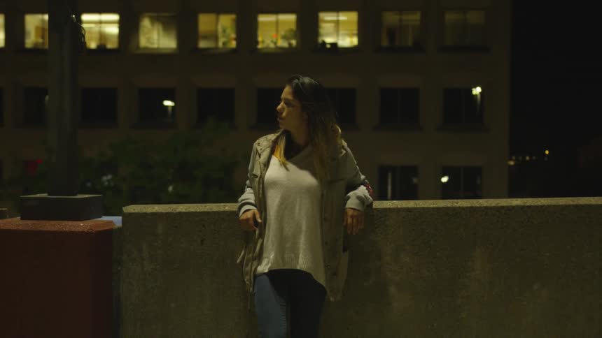 A woman stands outside in the city and looks around