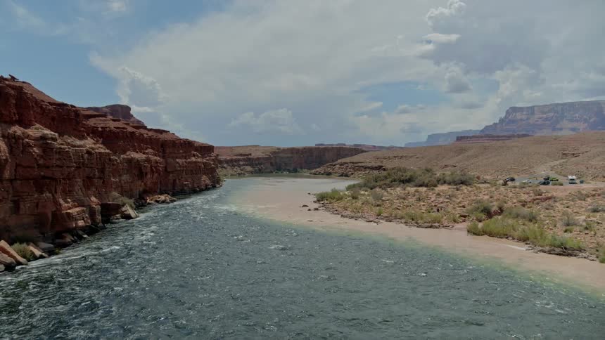 Red rock mountains with a river running onto the dirt