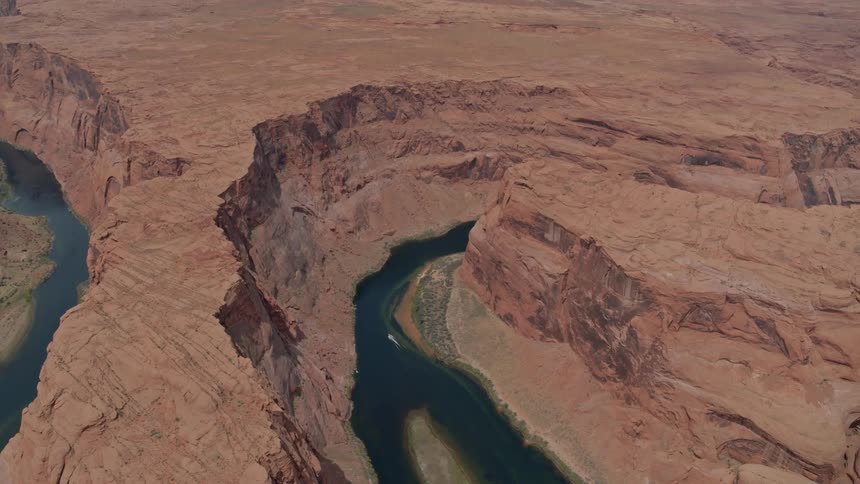 The red rocks of the grand canyon with a boat driving through the blue green river