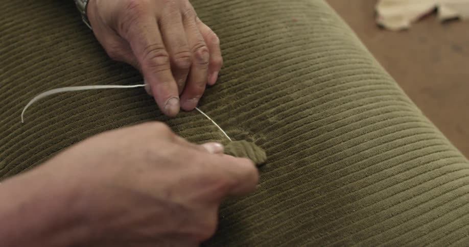 A person is attaching a button to a cushion