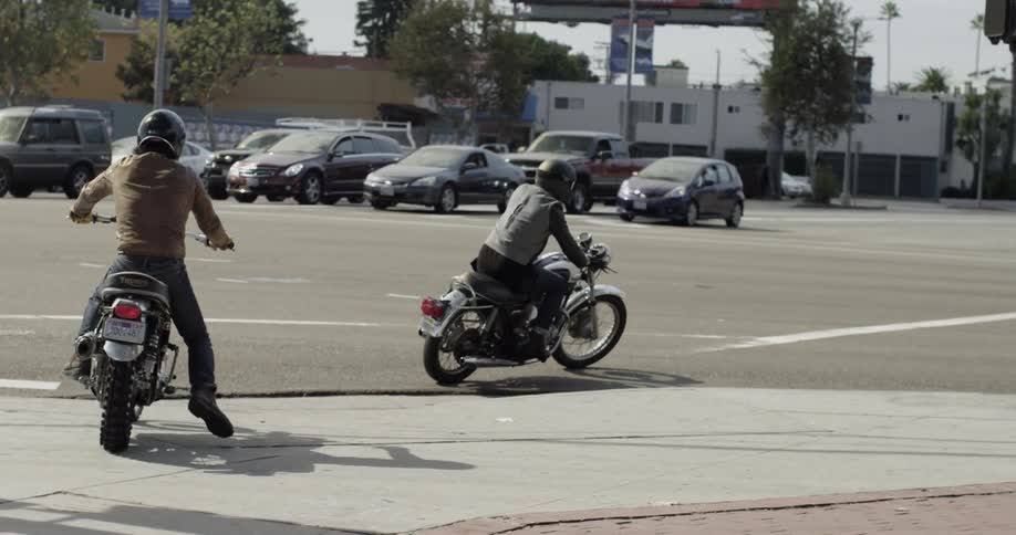 Two people drive into traffic on their motorcycles