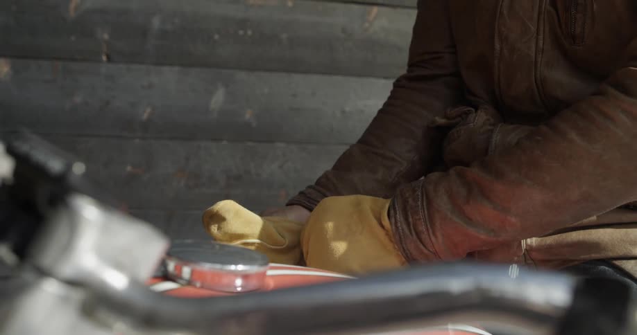 A person sitting on a motorcycle puts on gloves