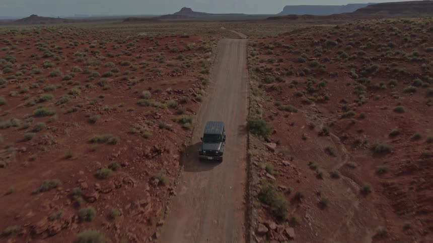 A car is driving on a dirt road in a remote area
