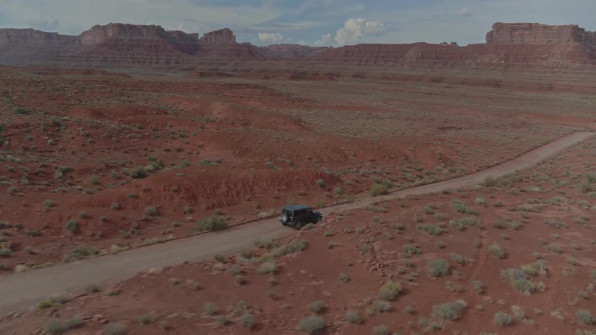 A car travels on a dirt road in a desert