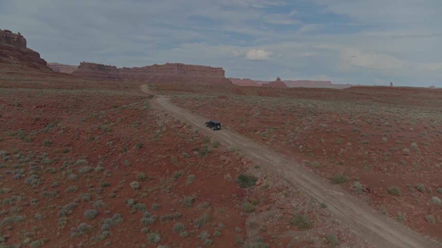 A suv drives through the desert at midday