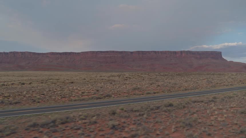 A silver vehicle drives down the desert road
