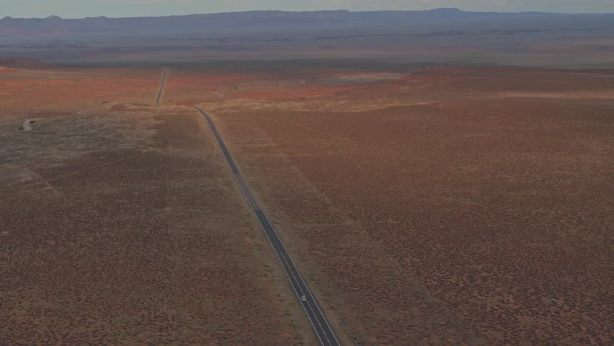 A view of a very large open area with a road with a single car on it